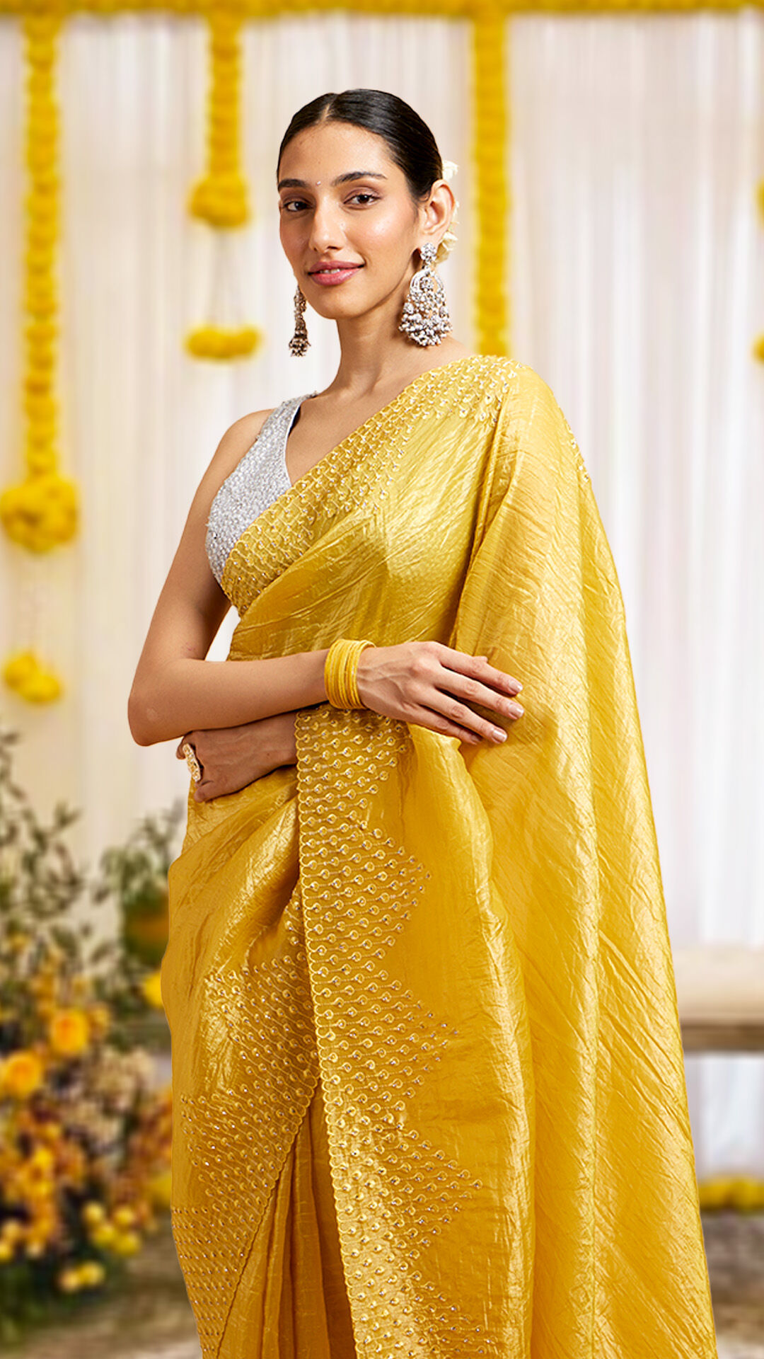 A woman elegantly dressed in a beautiful yellow saree, radiating festive charm.